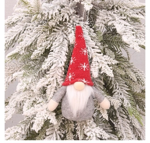 Close-up of a Christmas gnome ornament hanging on a snowy tree branch with festive detail