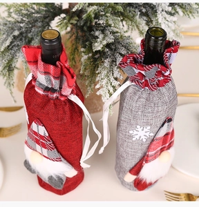 Detailed view of Christmas gnome wine bottle covers with red and gray plaid hats and snowflakes