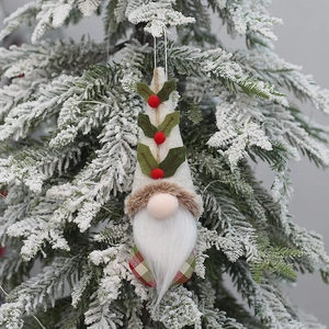 Close-up of handmade Christmas gnome ornament with holly leaves on a snowy pine branch
