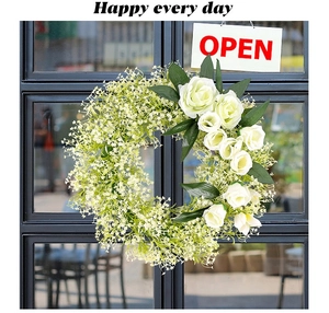 Detail of white rose and baby breath floral wreath on a black glass door frame