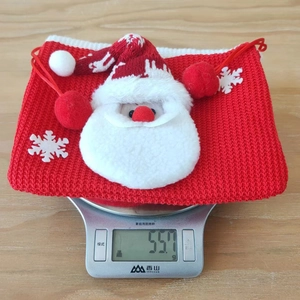 Detailed view of red knitted Christmas gift bag with Santa Claus figure on a digital scale