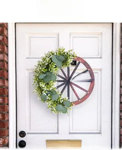 Détail d'une couronne de roue en bois avec eucalyptus et signe Welcome sur une porte d'entrée