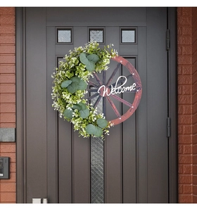 Détail de la plaque de bienvenue en roue de bois avec eucalyptus sur une porte d'entrée