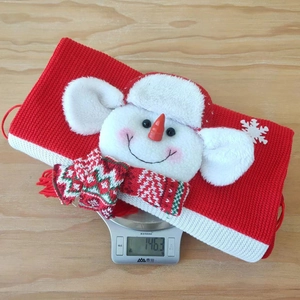 Close-up of red knitted Christmas gift bag with plush snowman on a digital scale