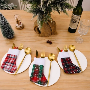 Three plaid Christmas stocking cutlery holders on a festive wooden dinner table