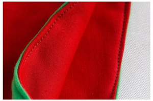 Close-up of red Christmas elf hat with green piping and precise stitching detail