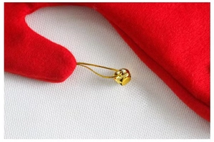 Detailed close-up of a festive red velvet elf hat featuring a shiny gold bell and stitching