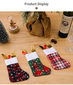Three plaid Christmas stocking cutlery holders with white snowflakes on a festive table