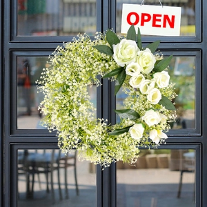 Artificial white rose and baby's breath wreath hanging on a door for wedding decor