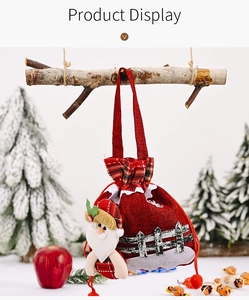 Detailed view of red burlap Christmas gift bag with plush Santa and festive pom-pom ties