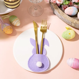 Close-up of purple felt Easter bunny cutlery holder with a white pom-pom tail on a plate