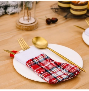 Plaid Christmas stocking cutlery holder with golden knife, fork, and spoon on a white plate