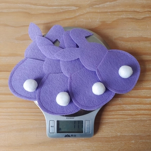 Detail of purple felt bunny Easter utensil holders with plush white tails on a scale