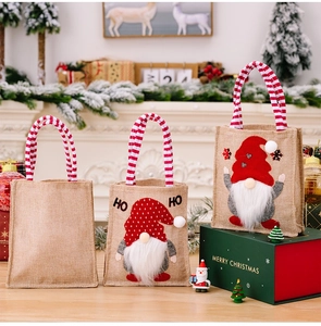 Detalle de bolsas navideñas de arpillera con aplicaciones de gnomos y asas de rayas
