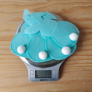 Close-up of blue felt bunny cutlery holders with white pom-pom tails for Easter decor