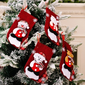 Detailed view of four small red linen Christmas stockings hanging on a tree with 3D characters