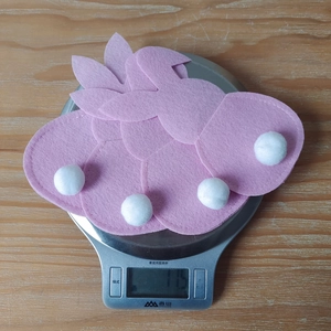 Pink felt bunny Easter decorations with white pompom tails and fine stitching detail