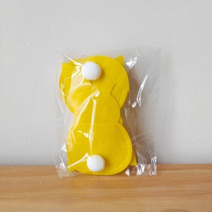 Detail of yellow Easter felt rabbit cutlery holders with white pompoms in packaging