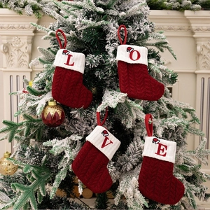 Detailed close-up of four red knitted Christmas stockings with LOVE embroidery hanging on tree