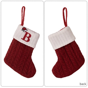 Detailed view of red knitted Christmas stockings with white cuffs and embroidered letter B