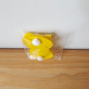 Detail of yellow felt Easter bunny cutlery holders with white pom-poms in transparent packaging