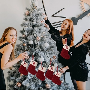 Red knit Christmas stockings with embroidered letters hanging on a holiday tree