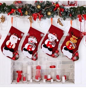 Detail view of 4-pack red burlap Christmas stockings with 3D dolls hanging on a white fireplace