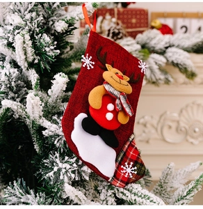 Detailed view of red burlap Christmas stocking with 3D reindeer hanging on a tree