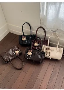 Detail of five PU leather tote bags in various colors with cute plush bear charms