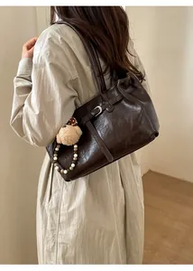 Detail of dark brown vintage pleated leather shoulder bag with plush puppy pendant