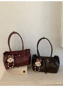 Detailed view of vintage pleated leather underarm bags in burgundy and deep brown colors