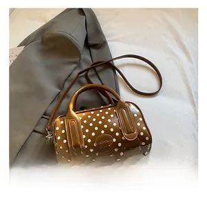 Primer plano de bolso Boston marrón de lunares con logo metálico sobre tela y blazer