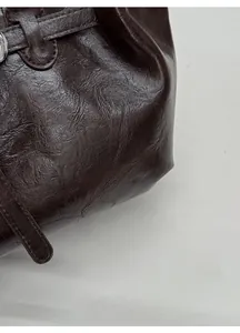 Detail of dark brown faux leather shoulder bag featuring rich oily texture and neat stitching
