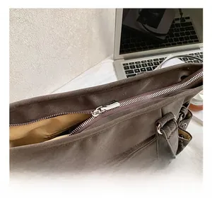 Detalle del bolso tote de ante marrón con cremallera de metal plateado y forro de tela
