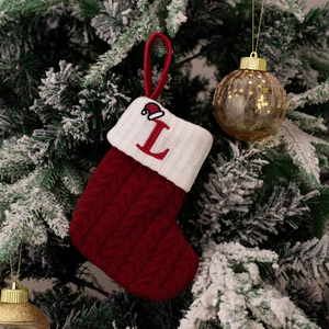 Detail of red cable-knit Christmas stocking with white cuff and embroidered letter L