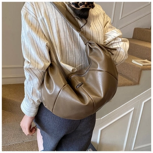 Detail view of coffee brown crescent bag with soft pleated matte leather and knotted strap