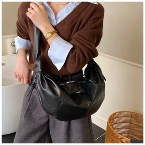 Detail of black crescent hobo bag with glossy leather texture and wide shoulder strap