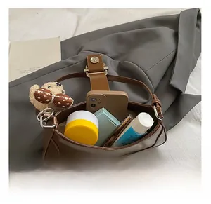 Détail montrant la capacité interne du sac en cuir marron avec téléphone et cosmétiques