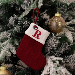 Macro detail of red knitted Christmas stocking with white cuff and embroidered letter R