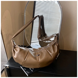 Detailed view of dark brown pleated crescent bag featuring an oval silver metal buckle