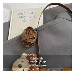 Détail de la bandoulière réglable en cuir marron avec un pendentif ours en peluche