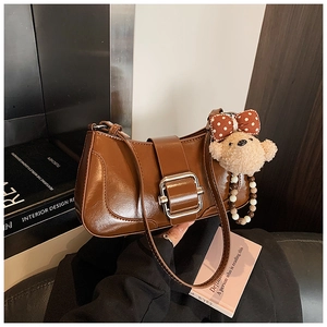 Détail du sac en cuir marron avec boucle en métal et charmant ours en peluche