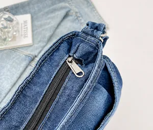 Detail des glatten Silber-Reißverschlusses und der Nähte an der dunkelblauen Denim-Tasche