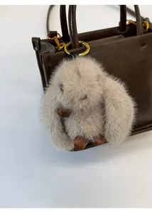 Gros plan d'un pendentif lapin gris pelucheux accroché à un sac fourre-tout en cuir