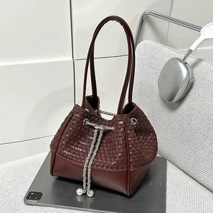 Détail du sac seau tressé bordeaux avec cordon en chaîne argentée et perles blanches