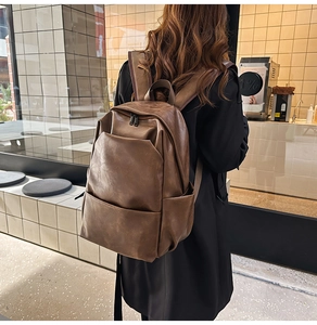 Rear view of a minimalist deep brown PU leather backpack on model in modern setting