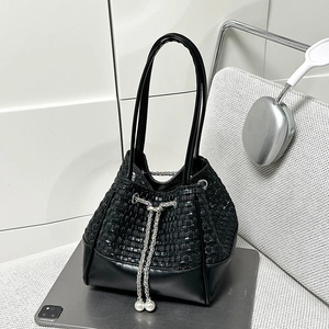 Détail du sac seau noir tressé avec cordon en chaîne argentée et accents de perles