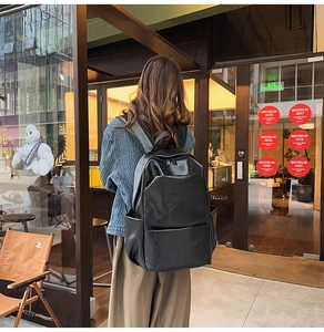 Outdoor shot showing the sleek black PU leather backpack silhouette on model's back