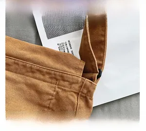 Primer plano detallado de las costuras reforzadas y herrajes del bolso de lona marrón