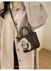 Détail d'un sac cabas en cuir marron foncé avec un pendentif lapin en peluche au design épuré